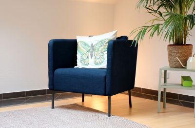 Blick in eine Raum mit einem blauen Sessel mit einem Kissen und gedämpftem Licht